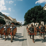 Rimania a Germáni v dobových kostýmoch pochodujúci centrom Trnavy. Fikcia generovaná AI. | Foto: red., úprava: Gemini